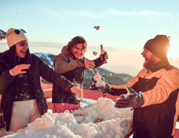 three friends celebrating outside on snowy day, beers in hand