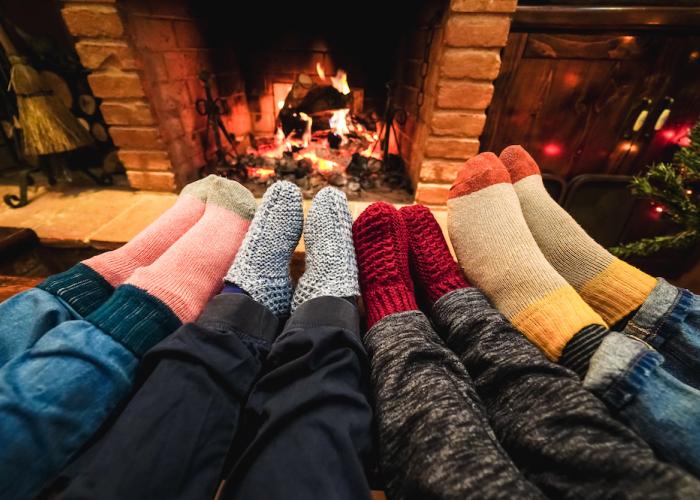 socked feet of four people, cozy around a fire