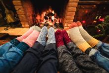 socked feet of four people, cozy around a fire