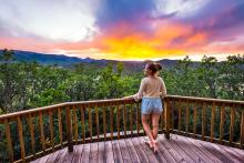 woman standing on balcony overlooking the mountains in Aspen at sunset