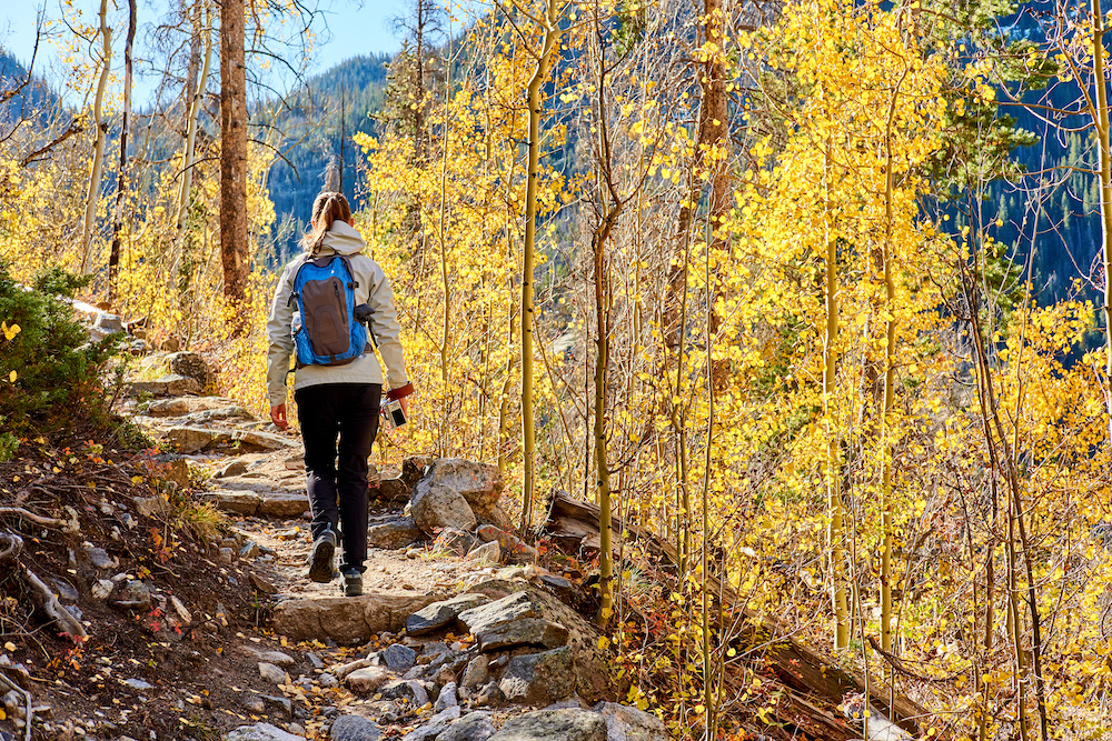 woman hiking up rocky stairs along a trail in Colorado