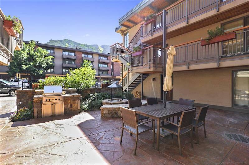 view of patio at aspen chateau with aspen mountain in the background with bright green foliage during summer