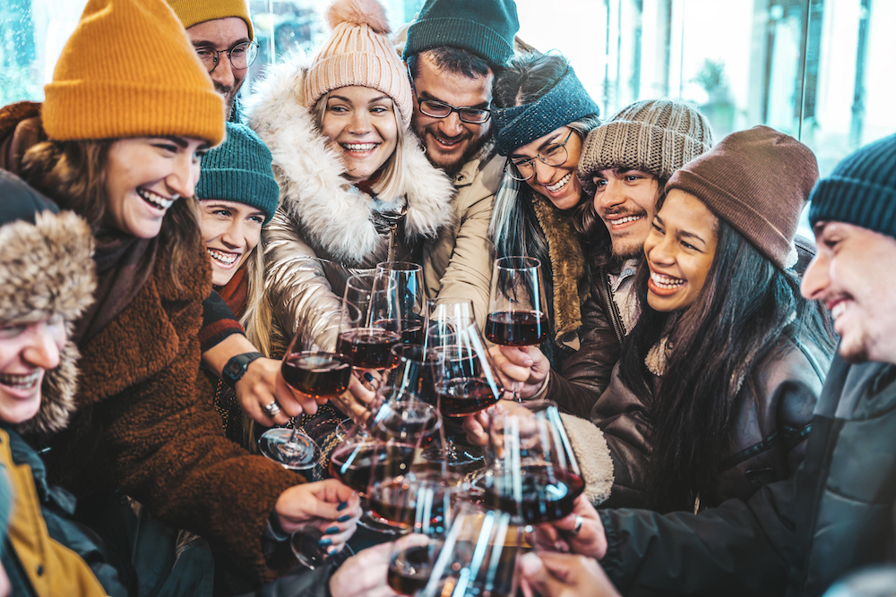 group of friends in winter clothes doing a cheers with wine glasses