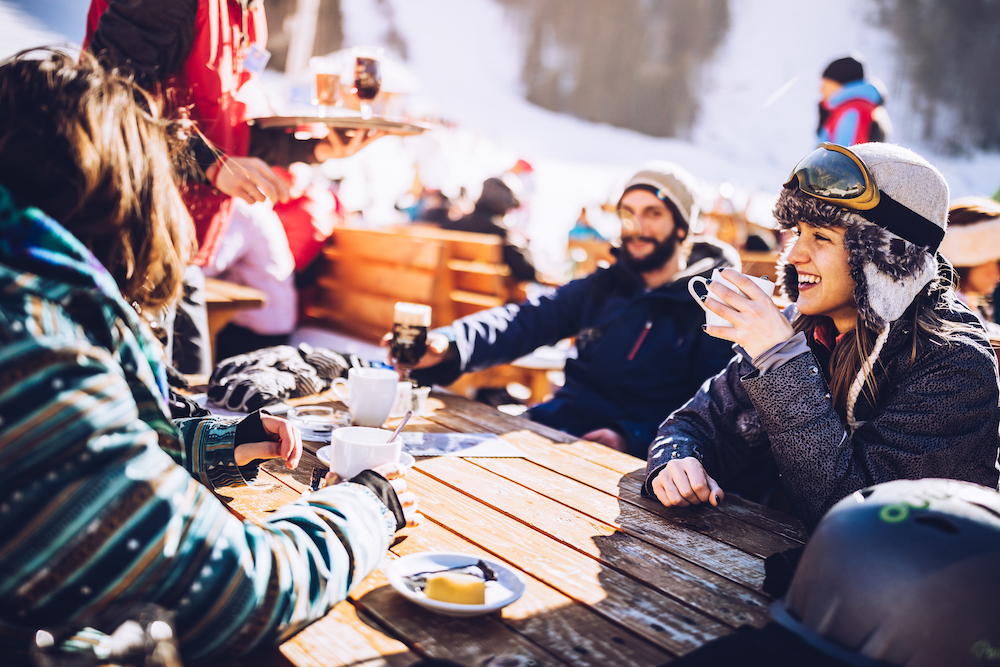 friends dining on a sunny day at a restaurant on a ski skope
